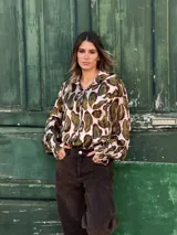 Camisa de manga larga con cuello camisero y cierre frontal de botones, confeccionada en tela fluida con estampado animal print en tonos marrones y negros.
