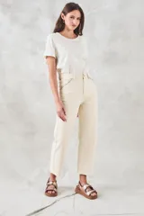 Pantalón jean color crudo, de tiro medio y corte recto, con bolsillos delanteros con bordado de motivos geométricos en tonos celeste y naranja.