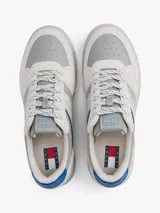 Zapatillas Tommy Jeans de corte bajo, confeccionadas en ante con paneles de malla y cuero sintético. Presentan un diseño en tonos gris y blanco con detalles en azul vibrante, cordones moteados y suela cupsole de goma con logo en bajo relieve.