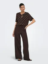Pantalón suelto color marrón con estampado de lunares blancos, tiro medio y cintura elástica con cordón de ajuste.