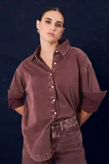 Camisa de gabardina con cuello clásico, cierre frontal de botones y mangas largas con puños vueltos. Presenta un diseño de corte recto y acabado desgastado.