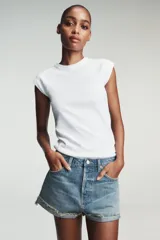 Shorts de jean de algodón, tiro alto, color azul claro desgastado. Presenta cinco bolsillos, cierre frontal con botón metálico y cremallera, y bajo desflecado con vuelta.