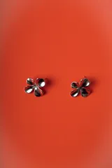 Aros con diseño de flor de cuatro pétalos de acabado plateado brillante y relieve cóncavo.