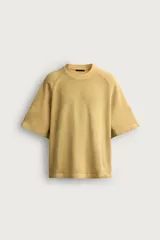Remera de corte relaxed fit, color mostaza, con cuello redondo y mangas ranglán cortas.