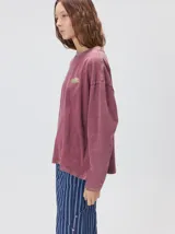 Remera oversize de manga larga color naranja con efecto gastado, cuello redondo y gráfico estampado en la espalda.