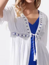Kaftan largo de playa color blanco, con mangas cortas, escote en V y detalles de puntilla en el frente. Presenta una abertura central con lazo de ajuste en la cintura.