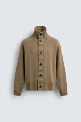 Chaqueta de punto de corte relajado, color marrón, con cuello subido, manga larga y cierre frontal de botones. Presenta acabados en rib en puños y ruedo.