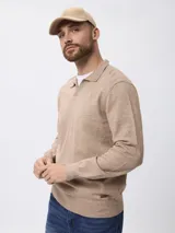 Sweater de punto color beige, con cuello polo y cierre frontal parcial, de manga larga y diseño clásico.