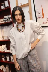 Camisa de corte holgado con estampado de rayas verticales finas en tonos beige y blanco. Presenta cuello redondo, cierre frontal oculto y mangas largas abullonadas con puños ajustados.