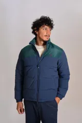 Campera puffer con diseño bicolor, cuerpo en azul marino y canesú superior en verde oscuro. Presenta cuello alto, cierre frontal completo y puños elásticos.