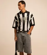 Bermuda baggy de jeans color gris oscuro con pespuntes contrastantes, cierre de botón y cremallera, y bolsillos.