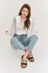 Sandalias de cuero color blanco con doble tira plateada con velcro, base negra y hebilla plateada.