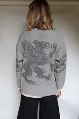 Buzo oversize de tejido de punto con diseño jacquard en mangas y espalda, cuello redondo y detalle de etiqueta de cuero sintético en el ruedo.