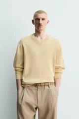 Sweater de punto en mezcla de algodón, color beige, con cuello en V y mangas largas. Presenta terminaciones en rib en cuello, puños y ruedo.