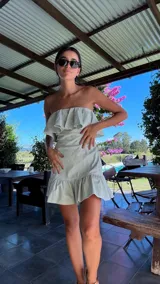 Vestido corto color verde claro, sin mangas, con escote recto con volados y falda con volados.