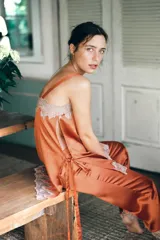 Pantalón de tiro medio confeccionado en tejido satinado, con cintura elástica y pernera recta. Presenta detalles de encaje y bordados en contraste en el ruedo.