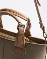 Cartera tipo tote XL de símil cuero con textura granulada en color verde, con dos asas de mano y correa bandolera regulable y desmontable en tono suela. Cuenta con cierre superior, costura central decorativa y parche frontal con logo en relieve.