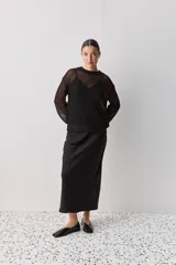 Falda midi color negro al bies, confeccionada en tela de textura suave y caída fluida, de diseño minimalista y silueta recta.