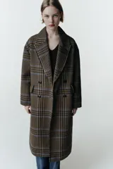 Abrigo largo de corte oversize con estampado de cuadros en tonos marrones y líneas azules. Presenta cuello de solapa, cierre frontal cruzado con botones, mangas largas y bolsillos delanteros con solapa.