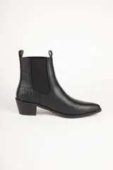 Botas de cuero negro con elástico lateral, caña baja, punta fina y taco bajo.