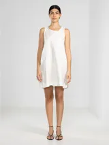 Vestido corto confeccionado en lino italiano con fibra metalizada que aporta un sutil efecto de brillo. Presenta un diseño sin mangas, cuello redondo, silueta holgada y aberturas laterales redondeadas. Incluye un detalle distintivo de la marca en la parte posterior.