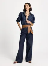 Camisa de jean de lavado oscuro, corte oversize, cuello camisero, mangas largas abullonadas con puños abotonados, cierre frontal con botones y pespuntes.