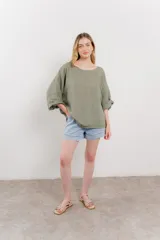 Blusa de lino color verde oliva, de corte amplio y relajado, con escote redondo y mangas 3/4 remangadas.
