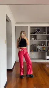 Pantalón rojo de cuero sintético, corte recto, tiro alto y costuras blancas a la vista.