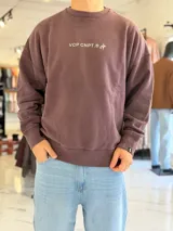 Buzo oversize de cuello redondo en color marrón con efecto gastado, con gran estampado en la espalda de estrellas y el texto VCP CNPT.
