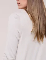 Cardigan largo de punto liviano y suave, de color blanco, con diseño abierto al frente, mangas largas con puños acanalados y bolsillos frontales aplicados.