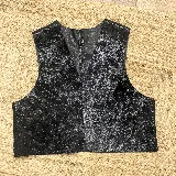 Chaleco de cuero negro con acabado texturizado y efecto desgastado en tonos plateados. Presenta un diseño sin mangas con escote en V profundo y cierre frontal.