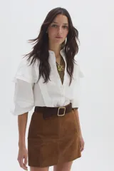 Camisa blanca de lino con cuello mao, volados en los hombros y mangas abullonadas con elástico. Cierre frontal con botones.