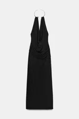 Vestido largo de color negro con cuello halter y detalle de aro metálico en el escote. Presenta un diseño drapeado en la parte frontal y escote en pico pronunciado.