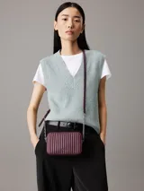 Cartera bandolera Calvin Klein color borgoña con diseño acolchado vertical. Tiene correa de cadena plateada, cierre superior con cremallera y logo metálico en el frente.