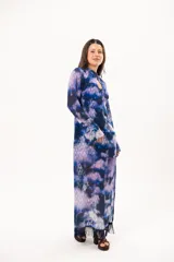 Vestido largo de manga larga con terminación campana, de color azul y violeta con estampado tie-dye, cuello mao con ojal y tajo frontal. Cuenta con flecos en el ruedo y tajo en la pierna.