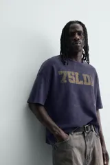 Remera de manga corta con corte relajado, confeccionada en tejido de algodón con textura tipo waffle. Presenta un efecto de lavado desgastado en color azul oscuro y estampado gráfico a contraste en el frente.