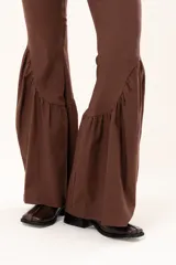 Pantalón de corte ajustado en la parte superior y pierna acampanada con volados en el ruedo. Presenta cierre frontal y bolsillos laterales.