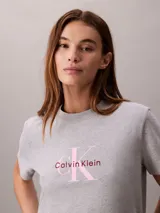 Remera gris melange de corte regular y manga corta, con cuello redondo y el logo de la marca en el pecho con letras rosadas y marrones.