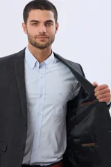 Saco sport de lana en color gris oscuro, con diseño clásico de solapa tradicional, cierre frontal de dos botones y bolsillos laterales con solapa.