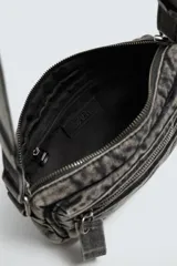 Bandolera de tejido denim con efecto lavado, cuenta con compartimento principal con cierre de cremallera, bolsillo interior con cierre y asa de hombro ajustable.