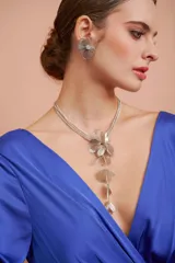 Collar plateado de triple cadena con dije de flor y racimo de pétalos colgantes.