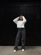 Pantalón de corte recto en color negro, confeccionado en tela elastizada de alta calidad. Presenta un diseño de tiro medio con detalle de tachas metálicas en la zona de los bolsillos delanteros.