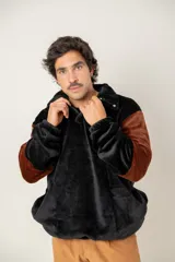 Buzo de textura afelpada en combinación de colores negro y marrón. Presenta cuello camisero con botones a presión, mangas largas y un diseño holgado y confortable.