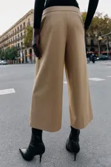 Pantalón tipo culotte de tiro alto, con pernera ancha y corta. Presenta detalles de botones dorados decorativos en la parte frontal y cierre lateral con cremallera oculta.