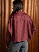 Campera corta de tela fina con diseño de paneles combinados, cuello camisero, cierre frontal con botones dorados y costuras a contratono.