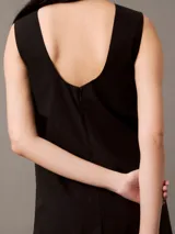 Vestido corto negro de popelín de algodón, corte evasé y diseño sin mangas. Tiene cremallera en la parte trasera central, está parcialmente forrado y cuenta con un bordado de Calvin Klein en la misma gama de tonos en el pecho.