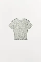 Top crop semitransparente de encaje color verde menta, con cuello redondo, manga corta y terminaciones onduladas. No incluye forro.