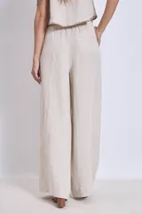 Pantalón de lino color beige, de corte amplio y tiro alto, con cintura elástica y bolsillos laterales.