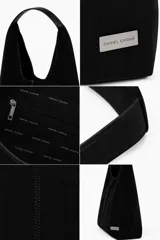 Cartera tipo hobo de gamuza negra con asa integrada y detalle de placa metálica con logo en la parte inferior.