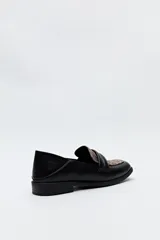 Mocasín negro de cuero sintético con punta cuadrada, detalle de textura en la capellada y taco bajo de 2,5 cm.